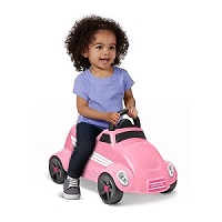 girl smiling and scooting on the pink race car with white stripes