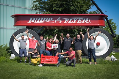 group of Radio Flyer employees pose in front of Worlds Largest Wagon with the Hero Wagon